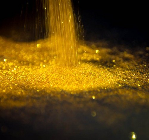 Pure gold dust found in mining, black background_